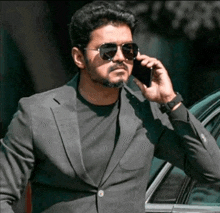 a man in a suit and sunglasses is talking on his cell phone