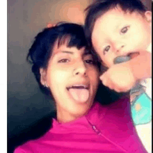 a woman is sticking out her tongue while holding a baby .