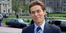 a man in a suit and tie is standing in front of a car