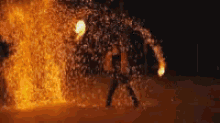 a person is standing in front of a large fireball .