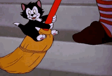 a cartoon cat is holding a broom in its paws and a witch is standing next to it .