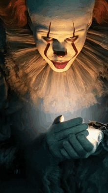 a pennywise clown is holding a light in his hands