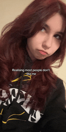 a girl with red hair is wearing a black shirt that says ' realizing most people don 't like me '