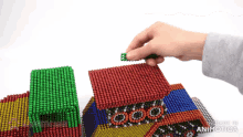 a person is playing with a stack of magnetic balls with the words made in animatica written on the bottom