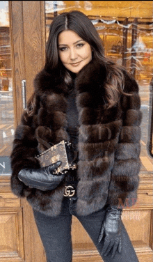 a woman wearing a fur coat and leather gloves holds a small purse