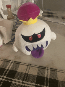 a stuffed ghost with a purple tongue and a pink crown