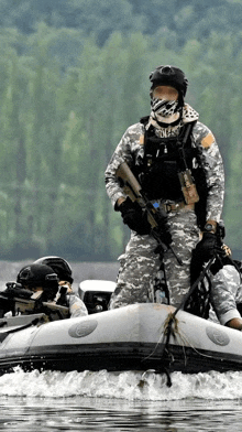 a man in a camouflage uniform is holding a gun while riding in a boat