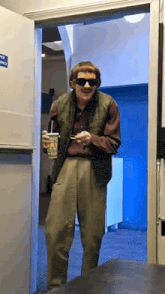 a man wearing sunglasses and a vest is holding a cup of ice cream