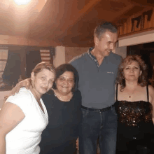 a man wearing a pierre cardin shirt stands with three women