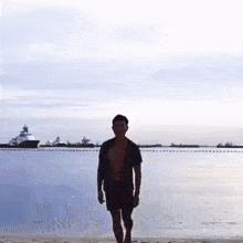 a man without a shirt is walking on a beach near the water .