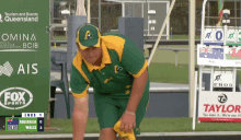 a man in a green and yellow uniform is standing in front of a scoreboard that says tourism and events queensland