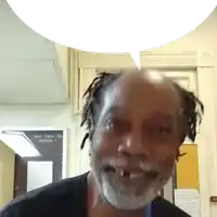 a man with dreadlocks and a beard smiles in front of a sign that says equality