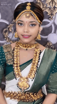 a woman wearing a green and white saree with gold jewelry