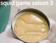 a person is holding a can of squid game saison 3 .