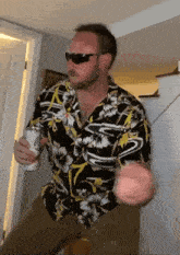 a man wearing a hawaiian shirt and sunglasses holds a can of beer