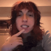 a woman with red hair is taking a selfie with her finger to her mouth