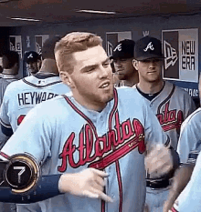 a group of baseball players are standing in a dugout . one of the players is wearing an atlanta braves jersey .