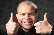 a man giving two thumbs up in front of a black background