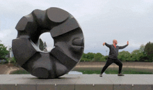 a man stands in front of a large sculpture that looks like a donut