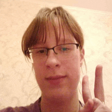 a woman wearing glasses is giving the peace sign