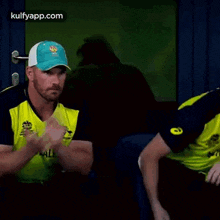 two cricket players are sitting next to each other in a dark room .