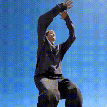 a man in a black sweater is kneeling down with his hands in the air