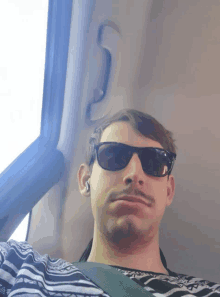 a man with a mustache wearing sunglasses and earbuds