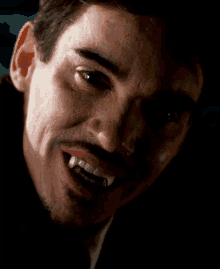 a close up of a man with vampire teeth on his mouth