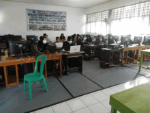 a group of people sitting at desks in front of a sign that says " selamat datang "