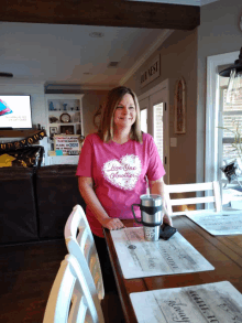 a woman wearing a pink t-shirt that says " love one another "