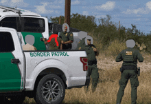 a group of border patrol officers standing next to a white truck