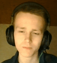 a young man wearing headphones and a microphone is looking at the camera .