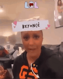 a woman is sitting on a couch with a beyonce filter on her head .