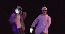 two men are dancing in a dark room with glow in the dark sticks .