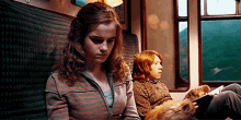 hermione granger and ron weasley are sitting on a train reading books .