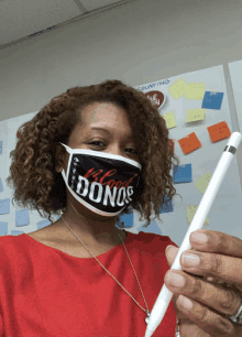 a woman wearing a mask that says blood donors holding a pen