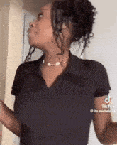 a woman with curly hair is wearing a black shirt and a choker necklace .