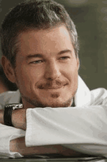 a close up of a man in a white lab coat with his arm resting on his elbow .