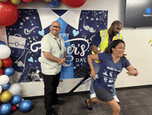 two men and a woman are posing in front of a happy father 's day poster