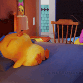 a yellow stuffed duck is laying on a bed next to a lamp and chair