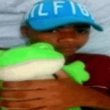 a man in a blue hat is holding a stuffed frog .