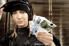 a man with dreadlocks is holding a bunch of euro bills in his hand