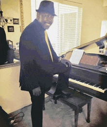 a man in a suit and hat is playing a piano .