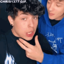 two young men are standing next to each other and one of them is wearing a chris1377 gif hoodie