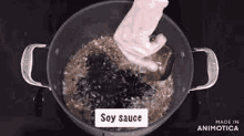 a person is putting soy sauce into a pot of food .