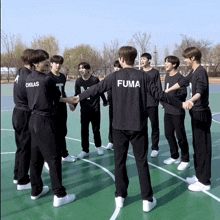 a group of young men are standing on a basketball court and one of them has fuma on the back of his shirt