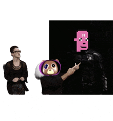 a woman stands next to a teddy bear and a man with a pink face on his head