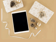 a tablet is surrounded by christmas decorations including pine cones