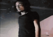 a young man in a black shirt is standing in a dark room