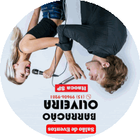 a man and a woman are upside down holding microphones in front of a sign that says barracao oliveira salao de eventos